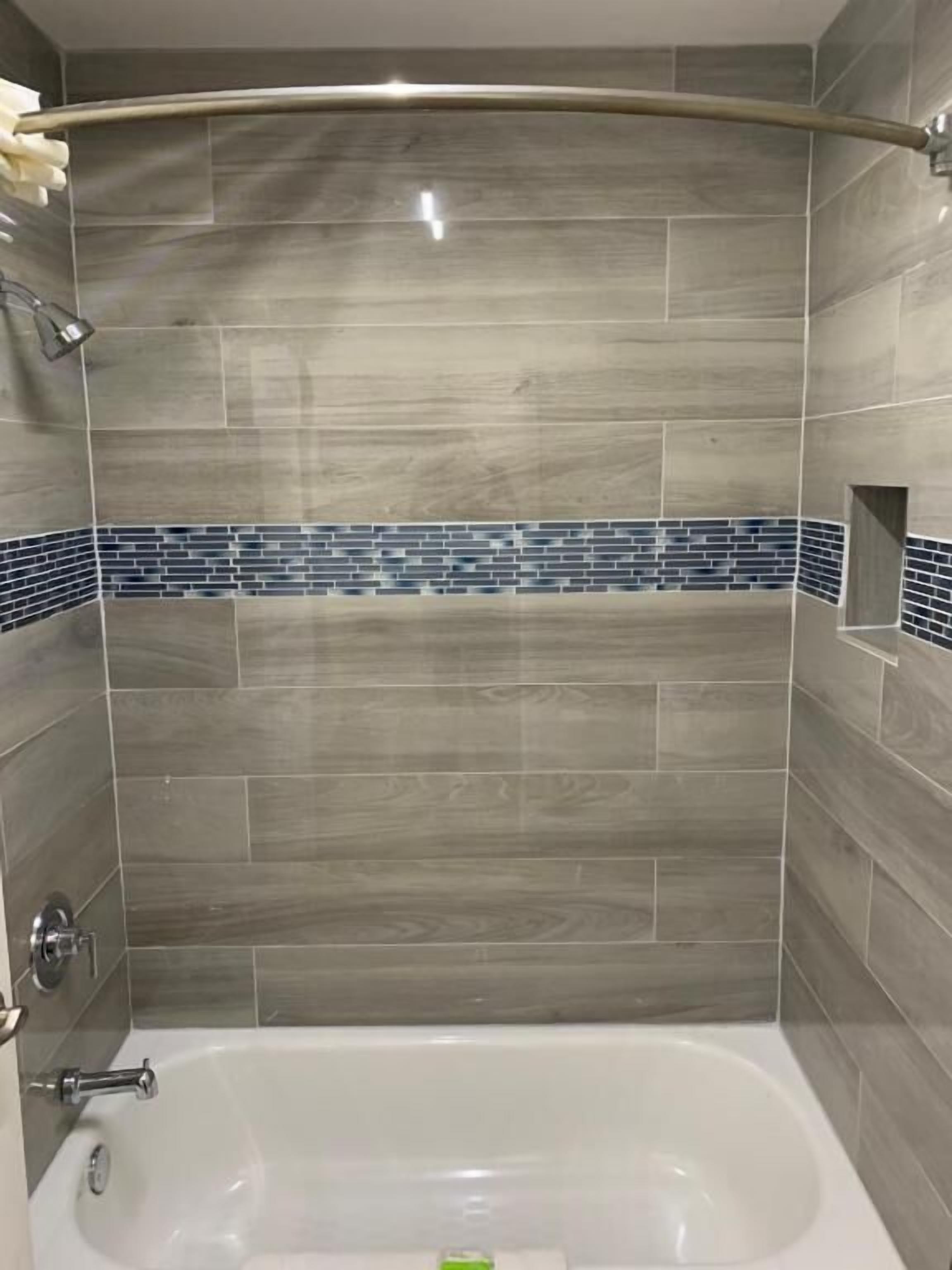 A bathroom with a bathtub, tiled walls, and a shower area.