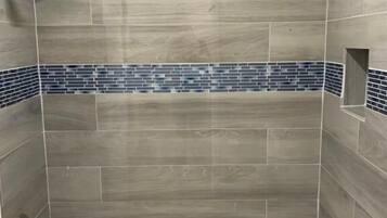 A bathroom with a bathtub, tiled walls, and a shower area.