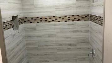 Un baño con bañera, paredes de azulejos y zona de ducha.