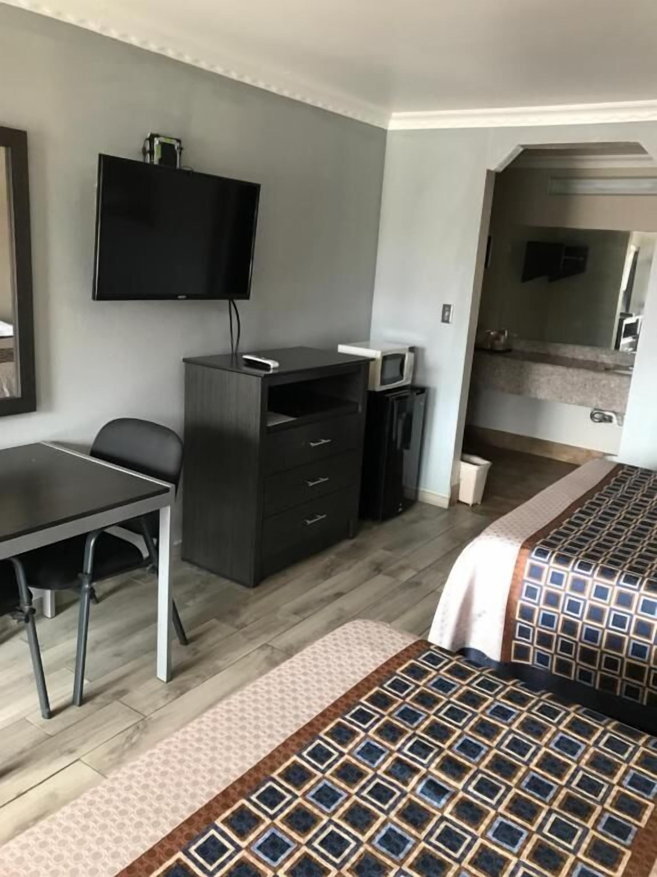 Ein Hotelzimmer mit Bett, Schreibtisch, Fernseher und Mikrowelle.
