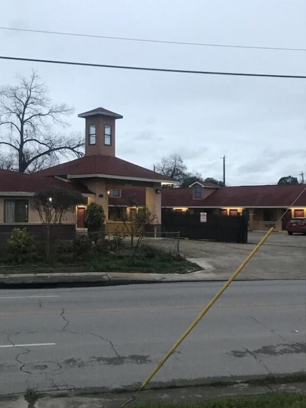 A building with a red roof and a small tower-like structure. There is a parking lot with a yellow line marking. - SouthTown SA Inn (San Antonio)