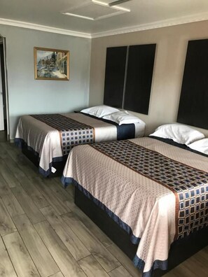 A hotel room with two beds, a painting on the wall, and a wooden floor. - SouthTown SA Inn (San Antonio)