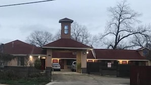 A two-story building with a central tower, a covered driveway, and a gated entrance. - SouthTown SA Inn (San Antonio)