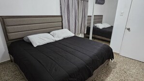 Een slaapkamer met een bed, een kledingkast, een spiegel en een plafondlamp.
