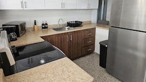 Een moderne keuken met witte kasten, een roestvrijstalen koelkast, een magnetron, een fornuis en een spoelbak.
