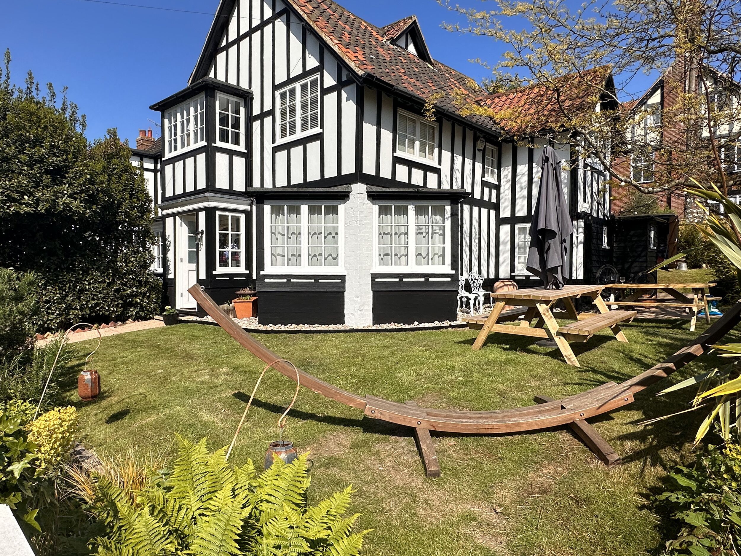 A traditional half-timbered house with a well-maintained garden, outdoor seating, and a swing set.