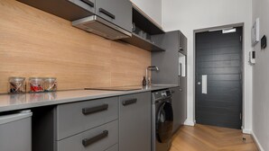 A modern kitchen with grey cabinetry, a built-in oven, and a washing machine.