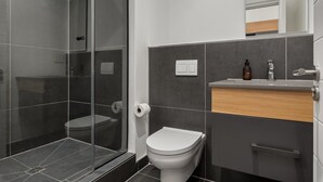A modern bathroom with a glass shower enclosure, a white toilet, and a vanity with a wooden countertop.