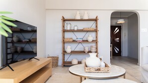 Un salon moderne avec un meuble TV en bois, une table basse ronde et une bibliothèque agrémentée d’objets décoratifs.