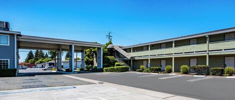 A motel with a parking lot, a gas station, and a staircase leading to the entrance.