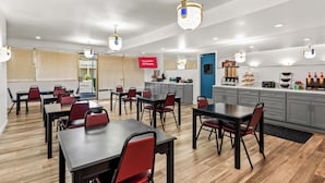 A modern hotel room with a dining area, kitchen, and a sign indicating free Wi-Fi availability.