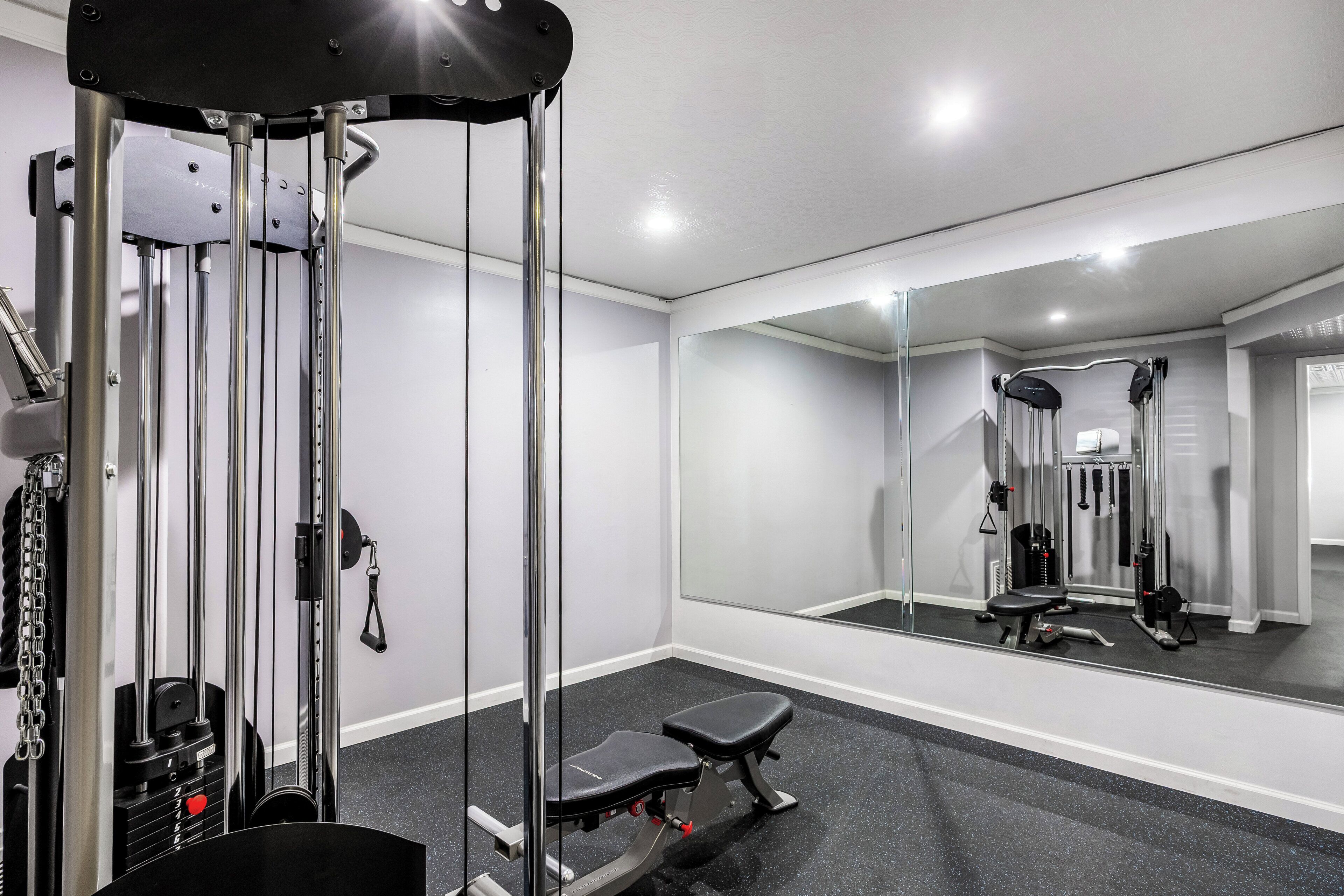 Un gimnasio con espejo, banco y diversos equipos de ejercicio.