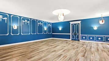 A spacious room with blue walls, wooden flooring, and decorative wall sconces.