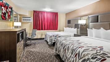 A hotel room with two beds, a desk, a chair, a large mirror, and a red curtain.