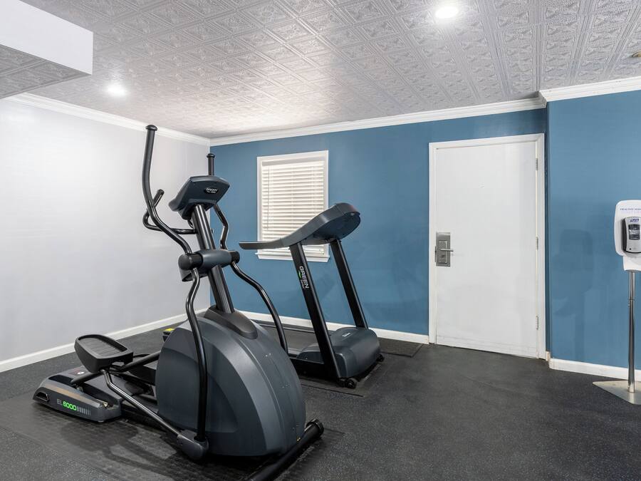 A fitness room with two treadmills, a stationary bike, and a water dispenser.