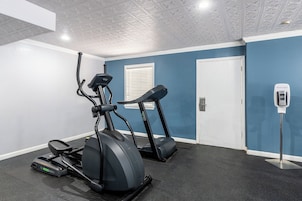 Un gimnasio con dos cintas de correr, una bicicleta estática y un dispensador de agua.