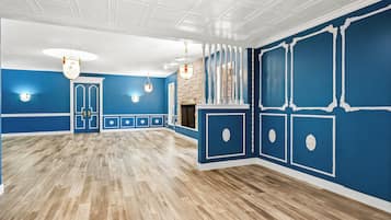 Une pièce spacieuse avec un plancher en bois, des murs bleus, des moulures blanches et une cheminée.