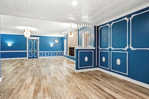 A spacious room with a wooden floor, blue walls, white trim, and a fireplace.