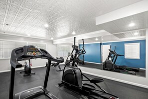 Un gimnasio con cintas de correr, elípticas y bicicletas estáticas.