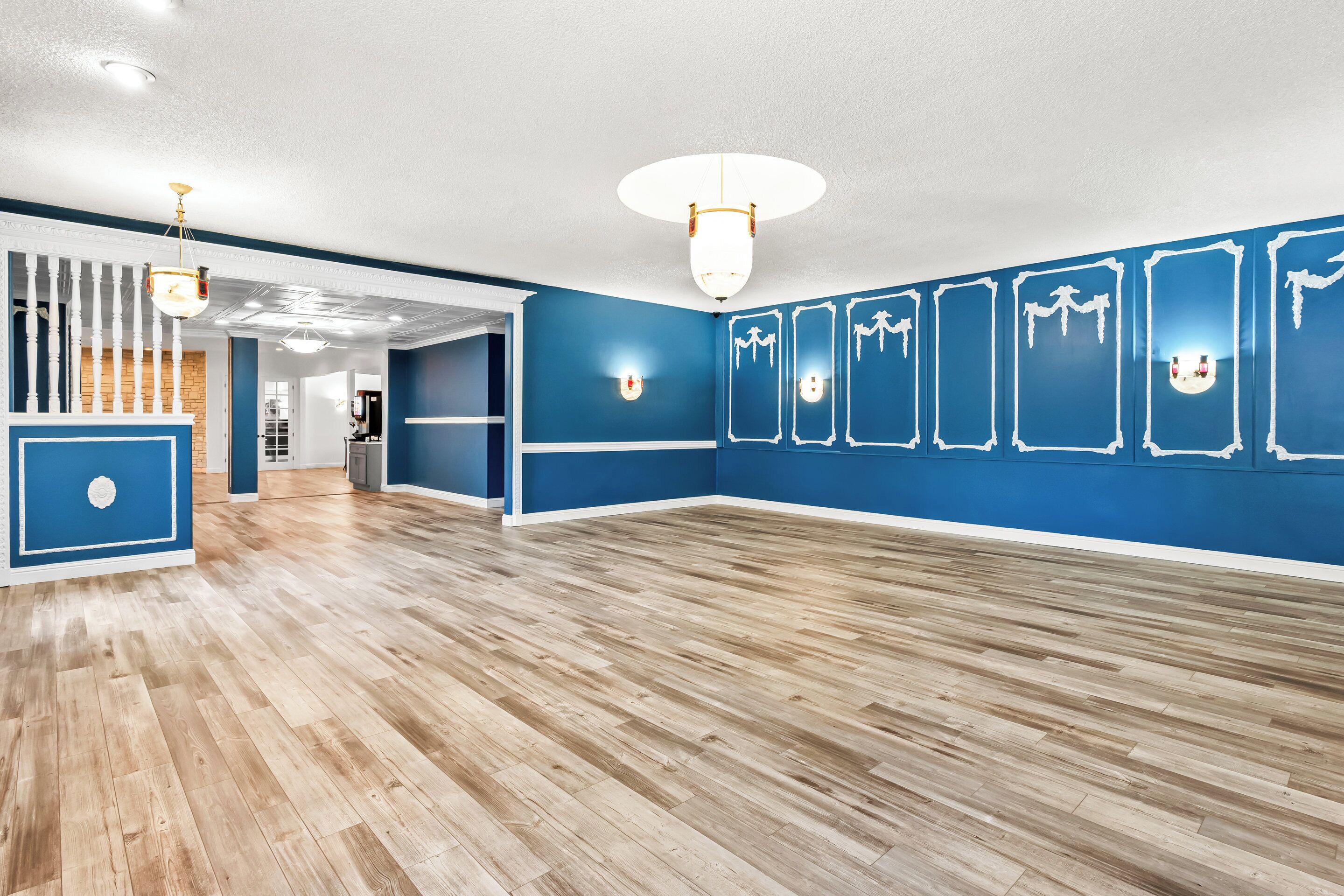 Una habitación amplia con suelo de madera, paredes azules y techo blanco.