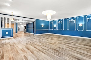 Una habitación amplia con suelo de madera, paredes azules y techo blanco.