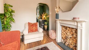 Un salon avec un canapé blanc, un fauteuil rouge, une cheminée et un grand miroir.