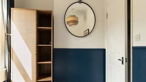 Une chambre à coucher comprenant un lit, une armoire, une porte et un luminaire fixé au mur.