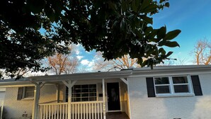 A single-story house with a front porch, a small front yard, and a clear blue sky. - Refined Home w/Game Room & Large Lounge (Westworth Village)