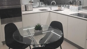 Eine moderne Küche mit einer zentralen Kochinsel, zwei schwarzen Stühlen und einem Glastisch.