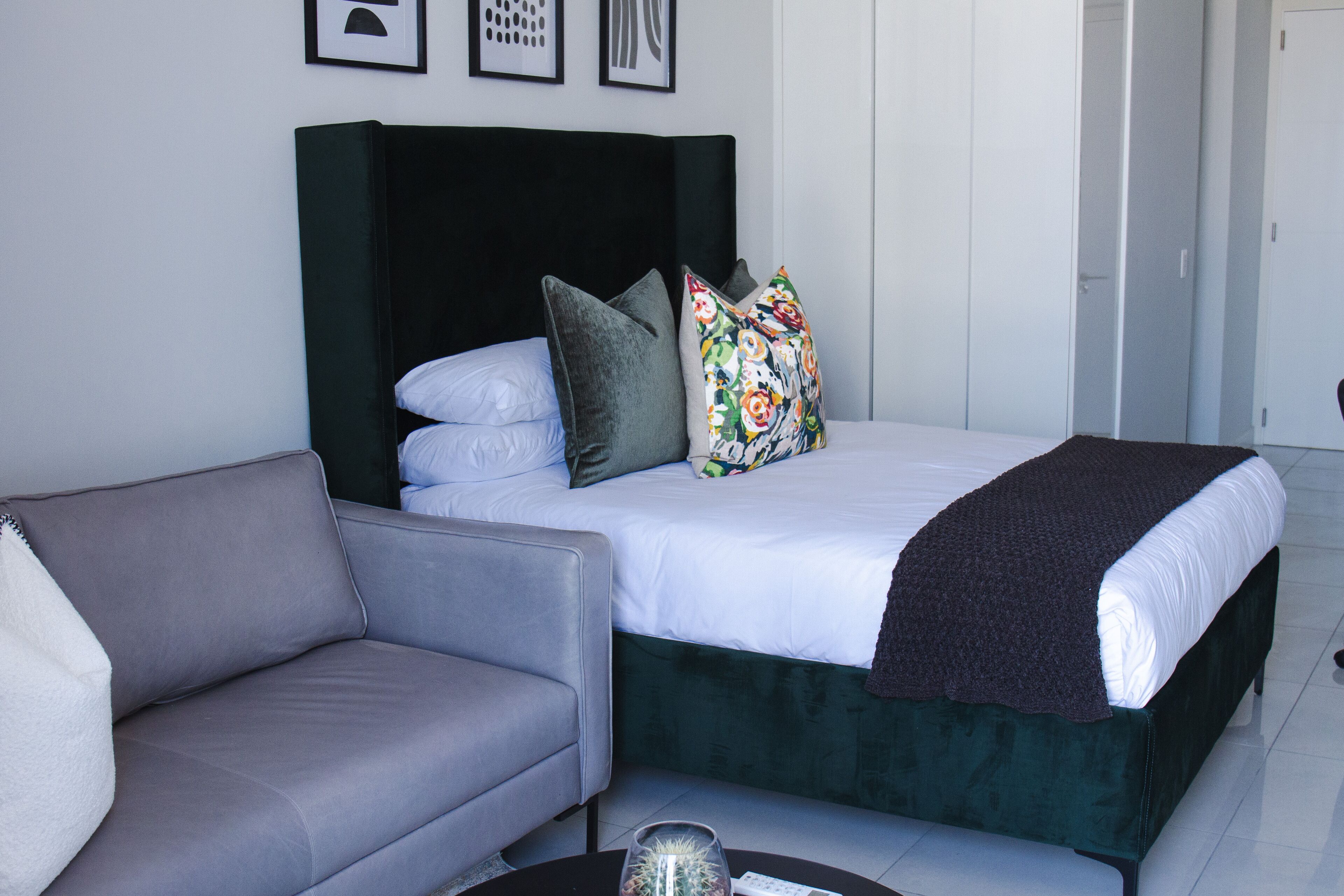 A bedroom with a bed, a grey sofa, and a coffee table.