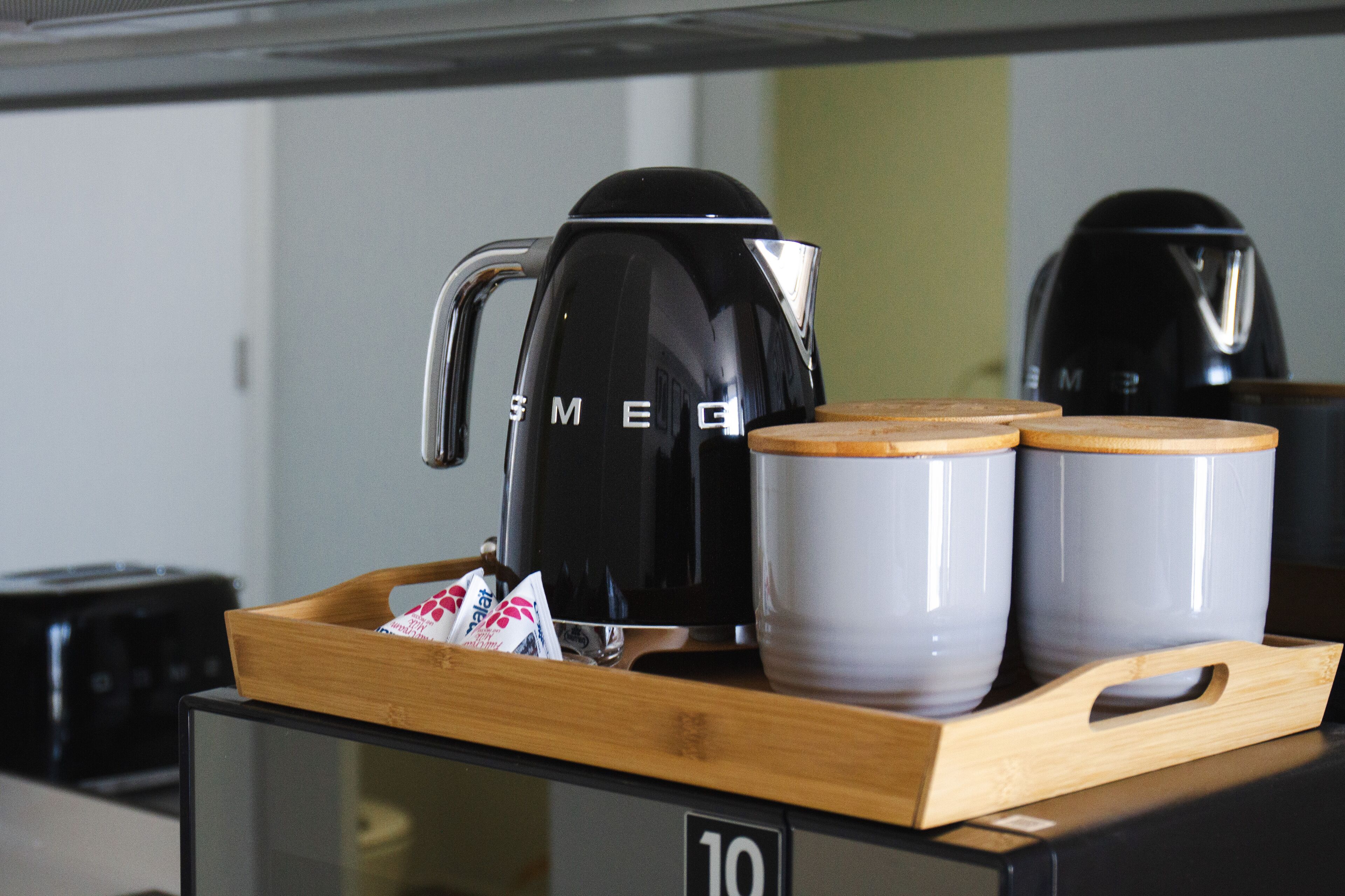 Un plateau avec une cafetière noire, deux tasses grises et un plateau en bois, le tout posé sur un comptoir sur lequel est affiché le numéro 10.
