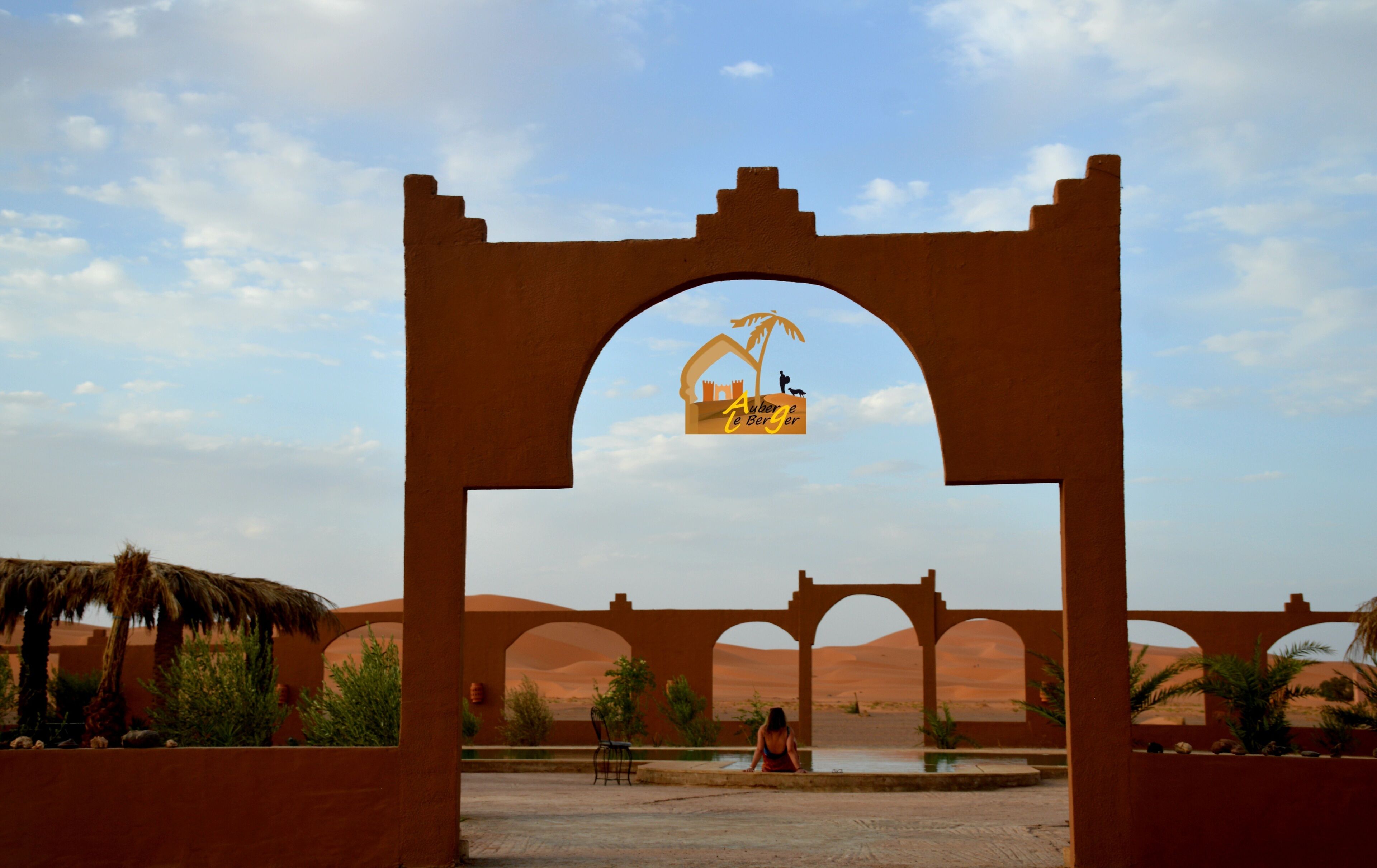 A desert landscape with a large archway and a sign above it.