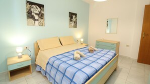 Une chambre à coucher comprenant un lit, des tables de chevet, une commode, un miroir et des œuvres d’art murales.