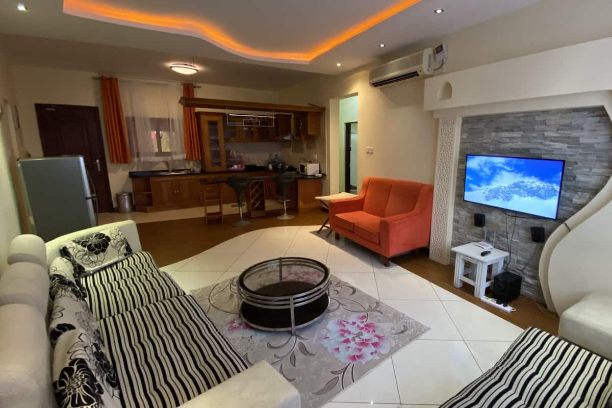 A living room with a sofa, a coffee table, and a TV mounted on a stone wall.