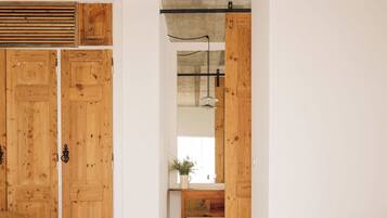 A room with wooden doors, a concrete ceiling, a striped rug, and a wooden bench.