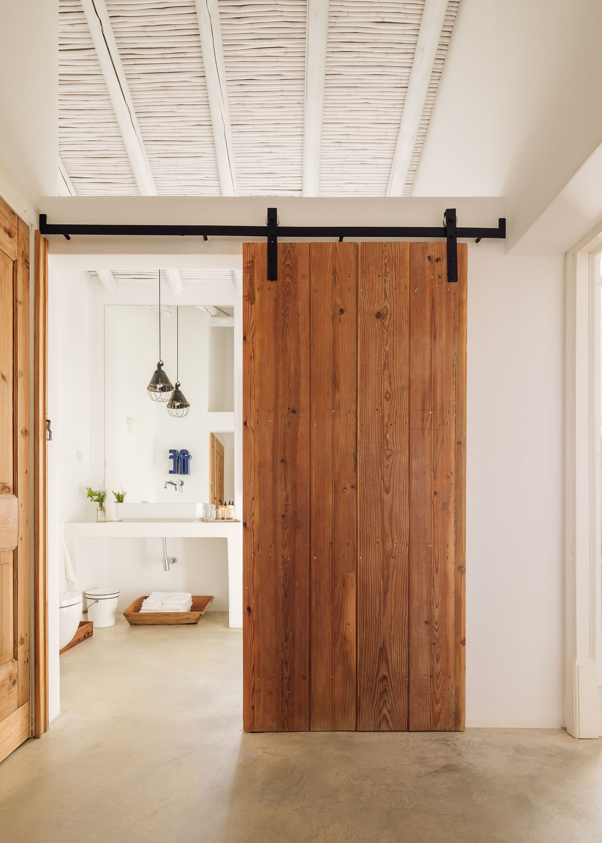 Un baño moderno con una puerta corredera de madera, un lavamanos blanco y un espejo.