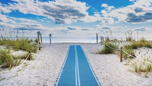 A beach path leading to the ocean, surrounded by sand and vegetation. - Beautiful 6 bedroom beach house with pool and elevator! Steps from the beach! (Oak Island)