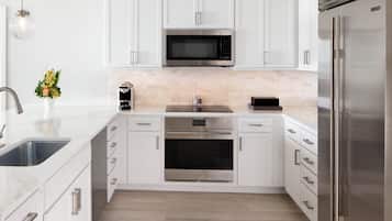A modern kitchen with white cabinetry, stainless steel appliances, and a wooden floor.