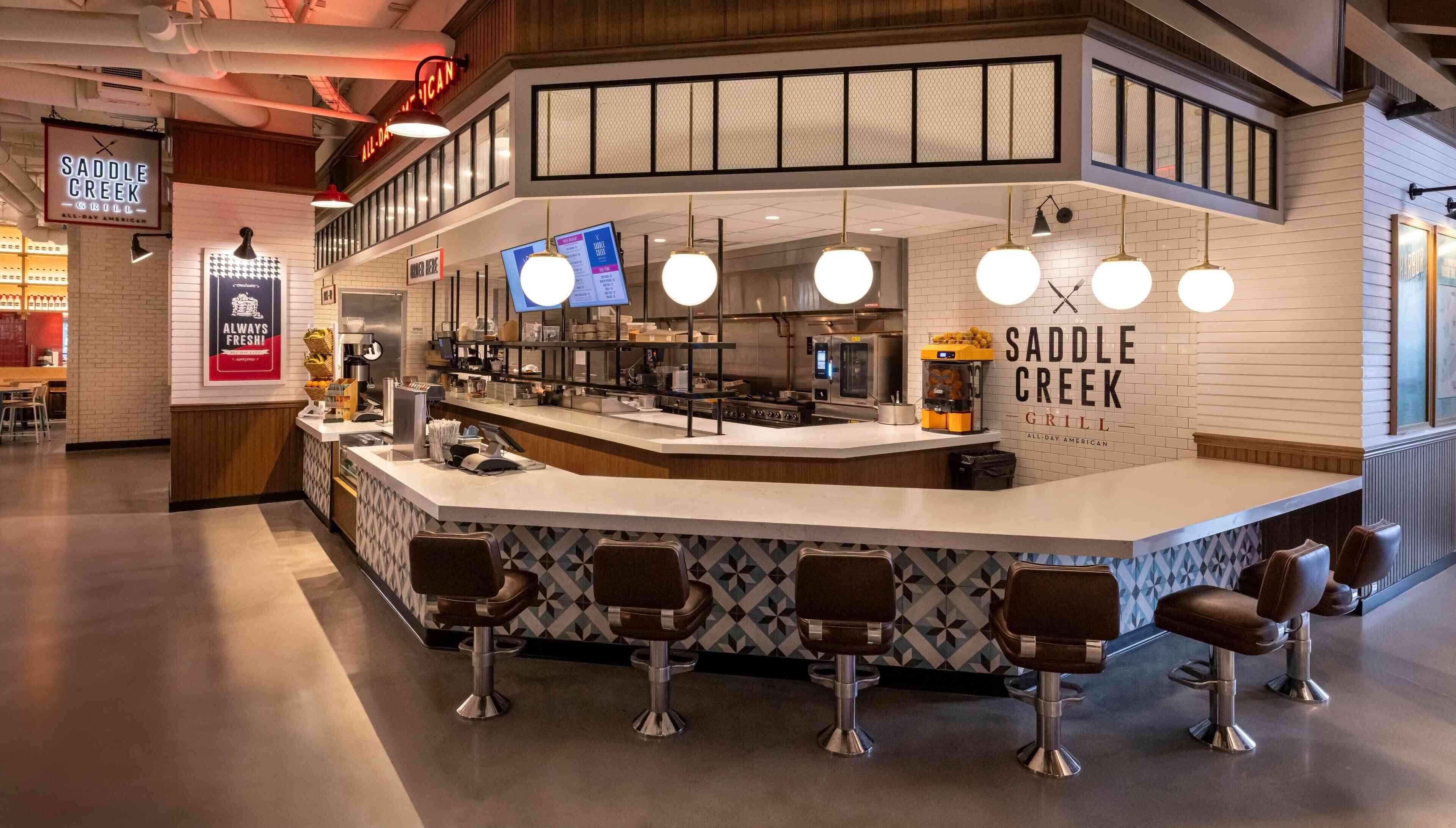 A modern restaurant with a bar area, seating, and a visible menu board.