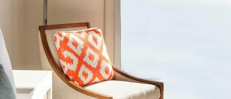 A chair with a patterned cushion in a room with a large window.