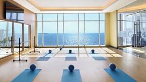 Een ruime kamer met grote ramen met uitzicht op zee, inclusief matten en yogaballen voor lichaamsbeweging.
