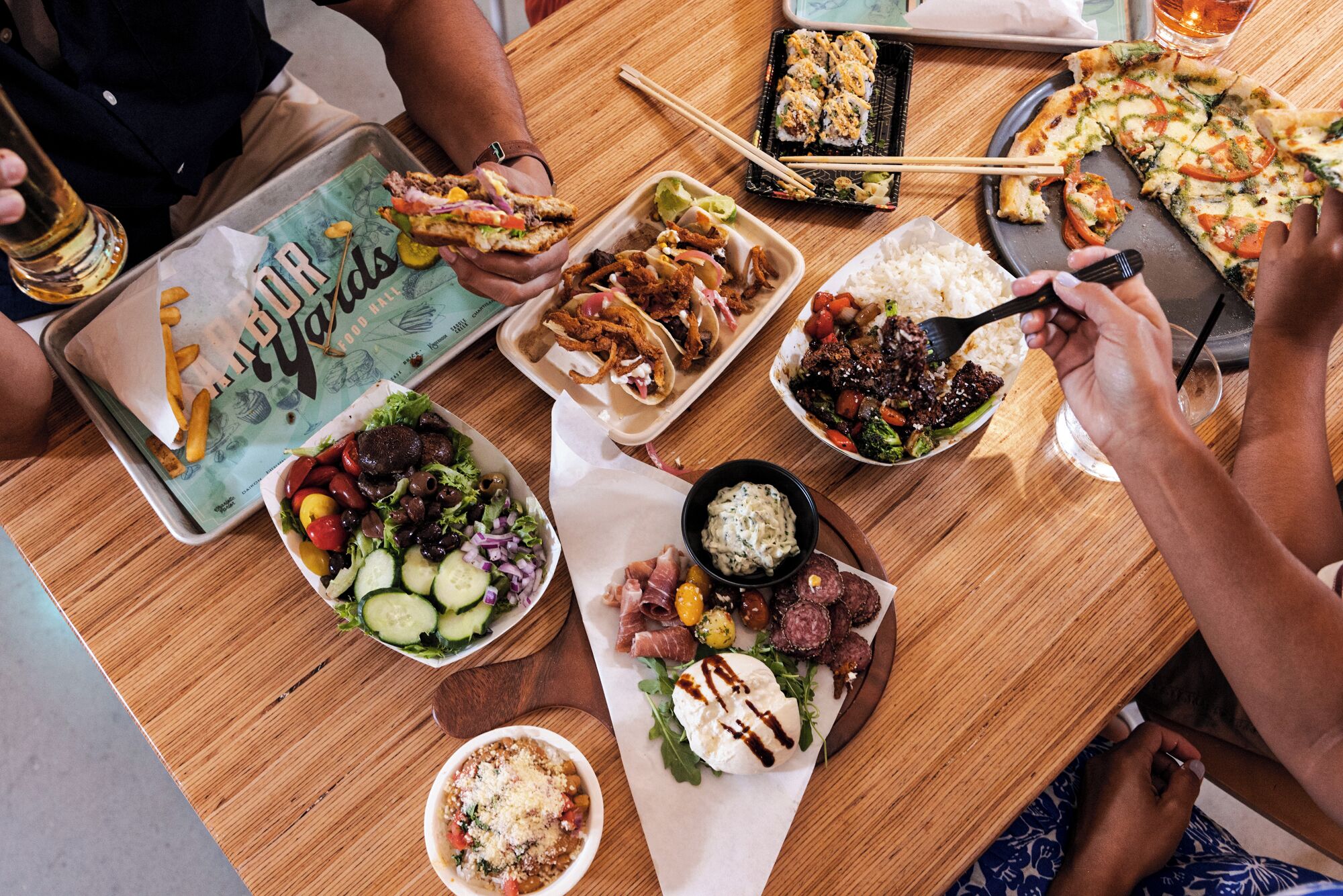 A table with various dishes including sushi, a burger, and a salad.