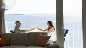 A couple toasting with wine glasses at a table with a view of the sea.