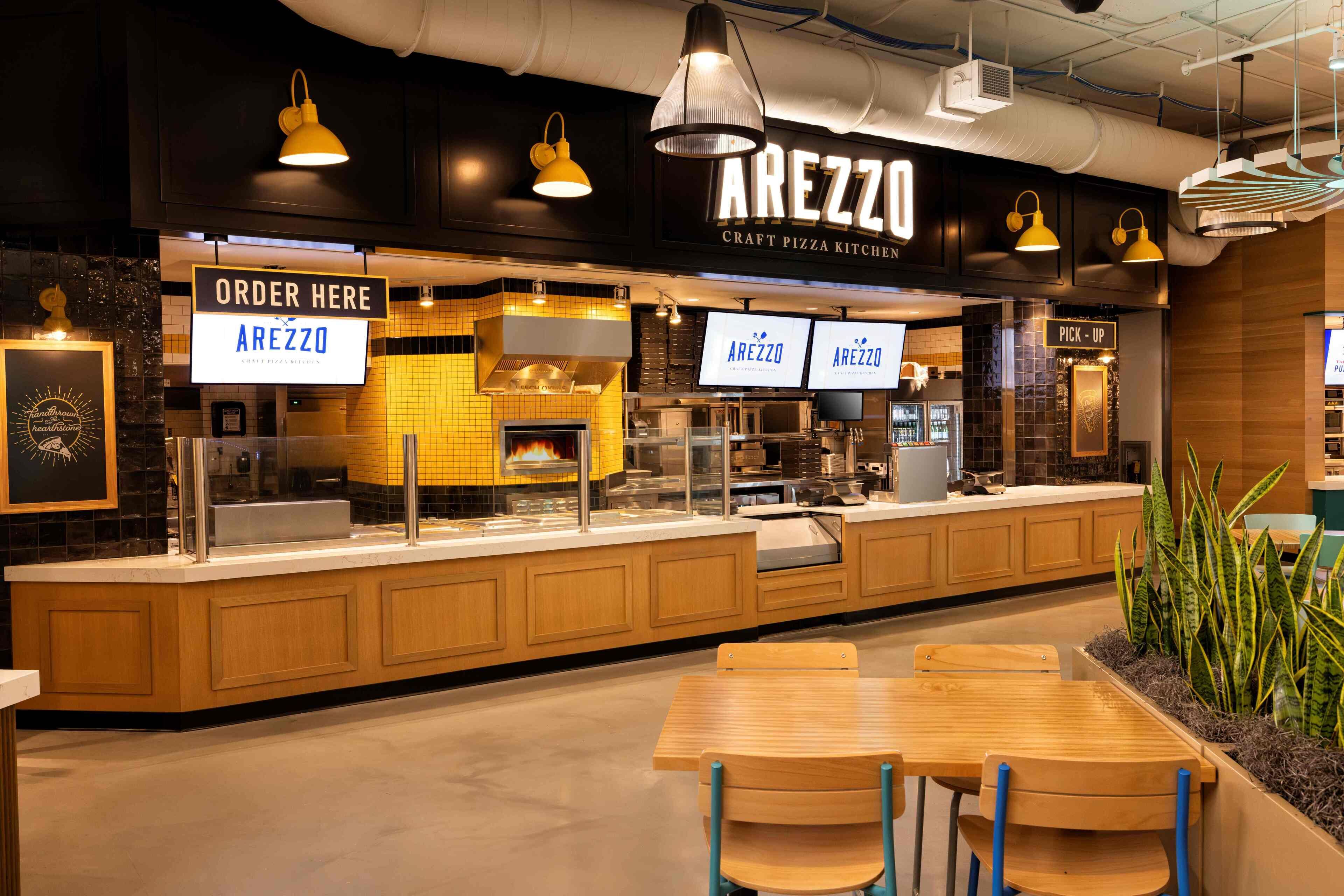 A craft pizza kitchen with a counter, seating area, and a 'PICK-UP' sign.