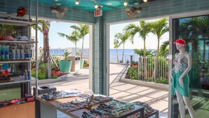 Interieur van een boetiekhotel met uitzicht op het strand, een etalagepop en diverse tentoongestelde objecten.