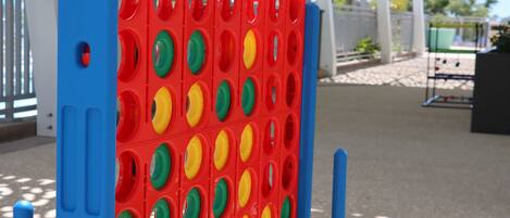 Un tablero de juego rojo y azul con agujeros, colocado al aire libre sobre una superficie pavimentada.