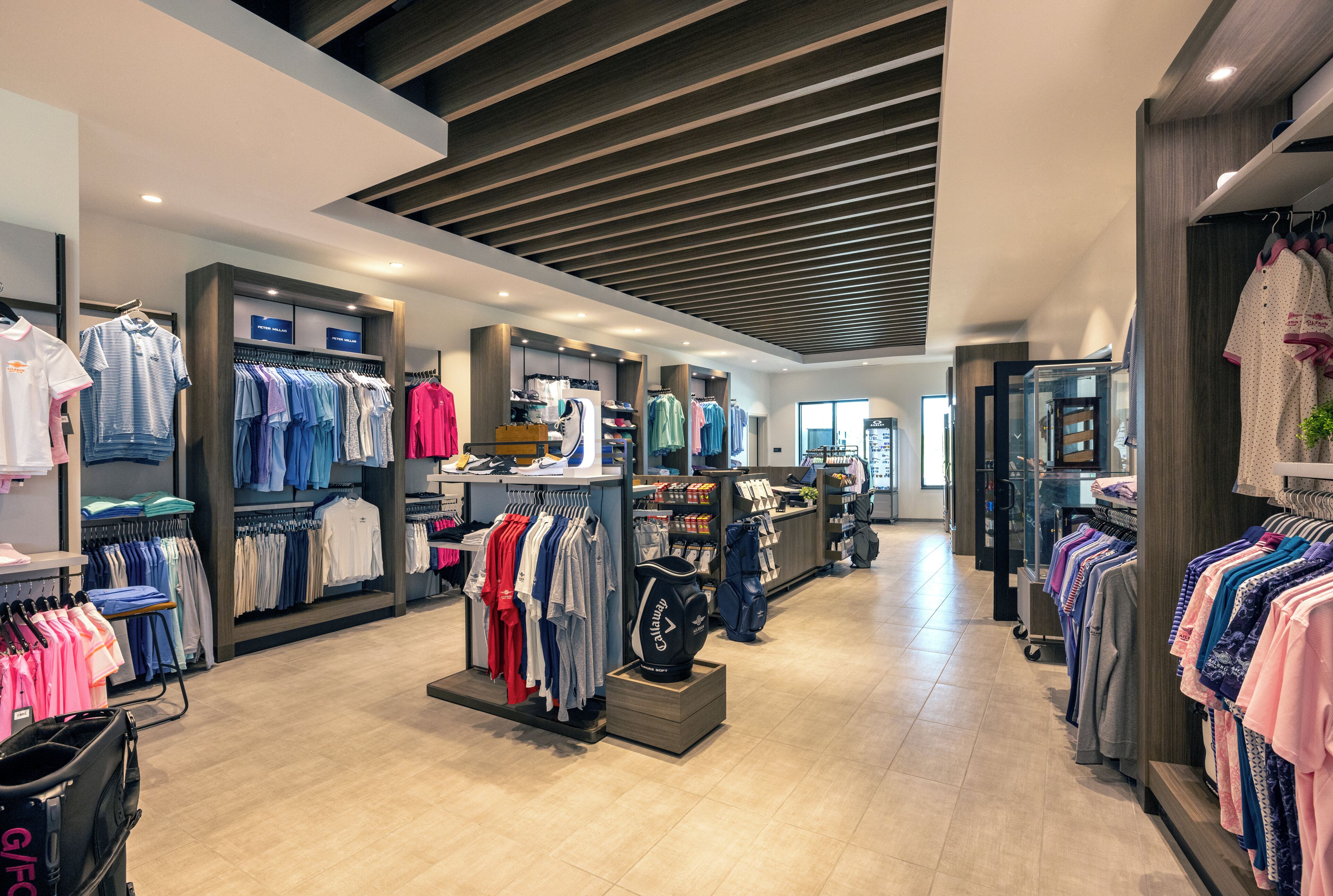 A modern retail store with clothing racks and shelves, wooden ceiling, and a clean, organized layout.