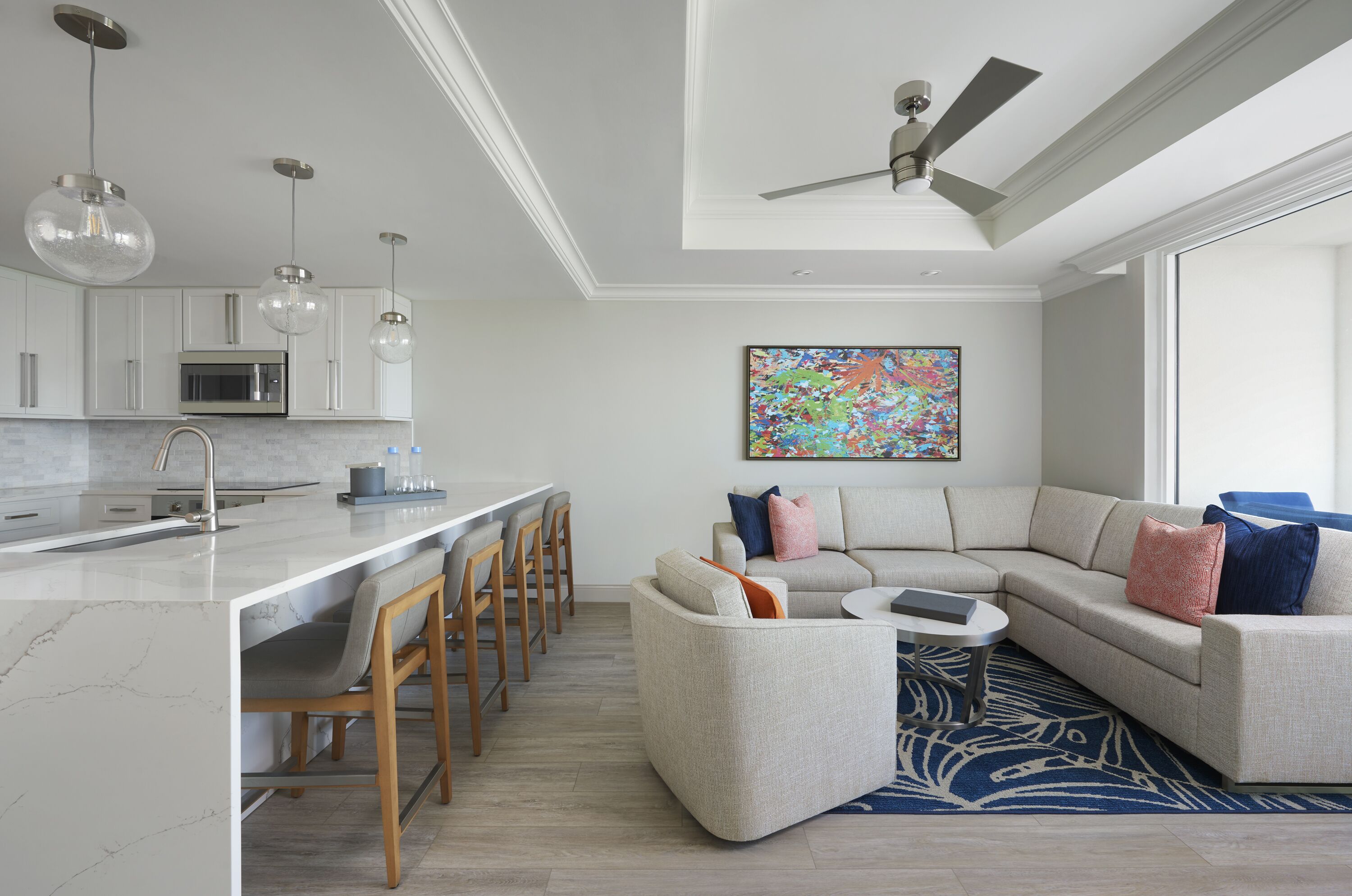 A modern kitchen with a central island, bar stools, and a dining area.