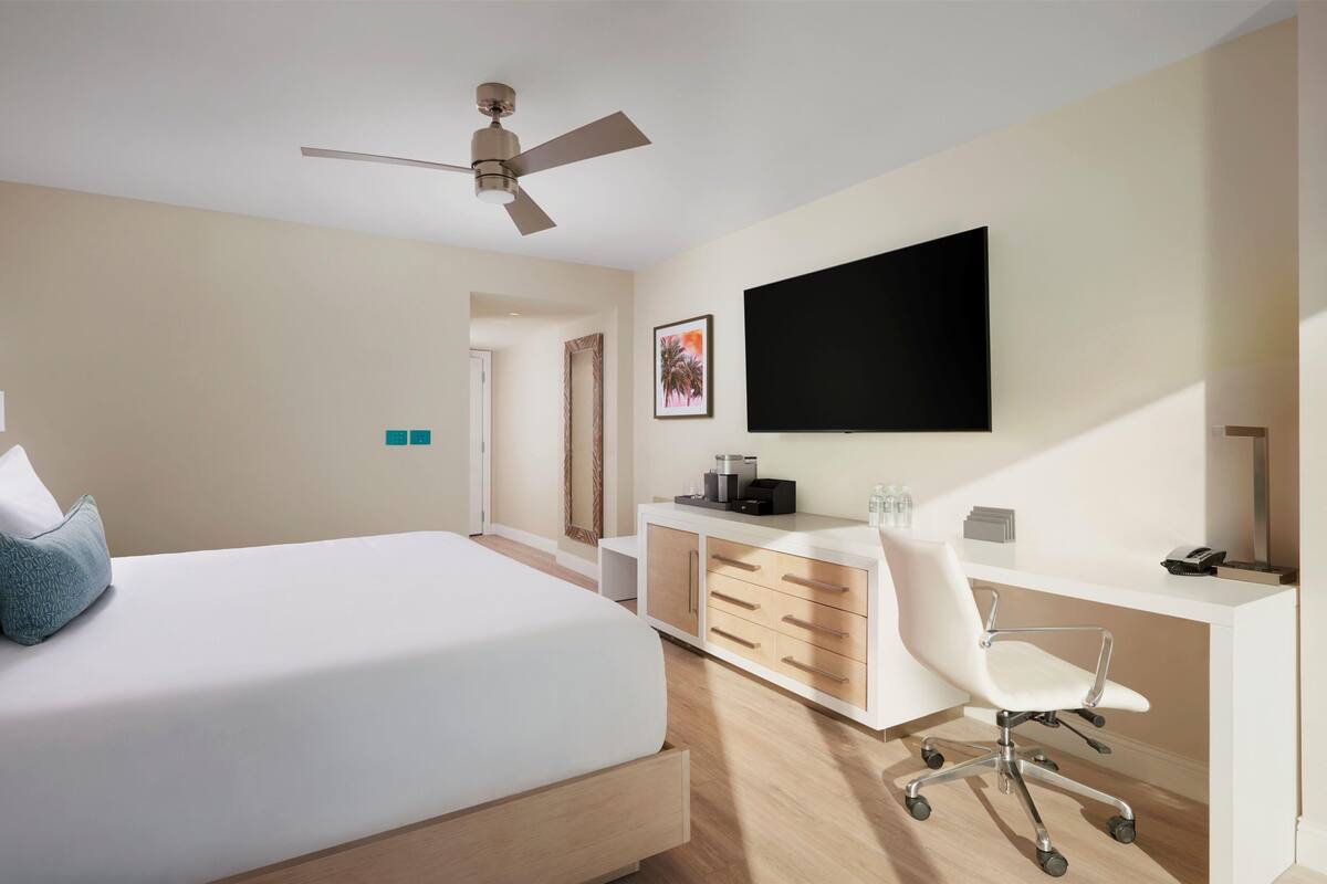 Une chambre d’hôtel moderne équipée d’un lit, d’un bureau, d’une chaise et d’un téléviseur à écran plat.