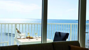 Een balkon met een tafel gedekt voor twee personen, met champagne, glazen en een schaal fruit.